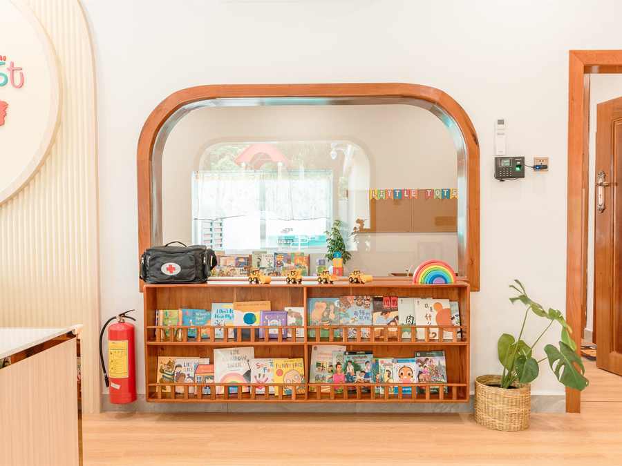 Low wooden shelves filled with picture books beneath a curved timber arch