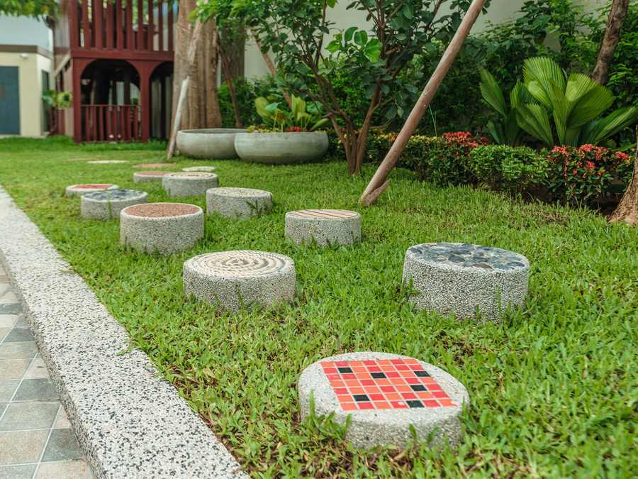 Stepping stones set into the lawn winding between planting beds in the school garden