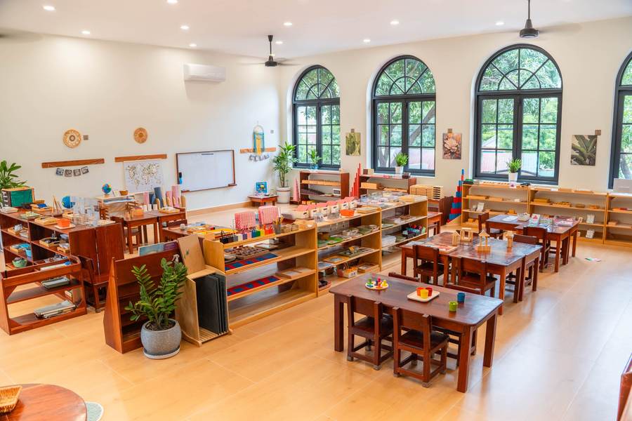 A Montessori classroom at Orange Crest Preschool: low wooden shelves of materials, child-sized tables and the arched windows of the renovated building