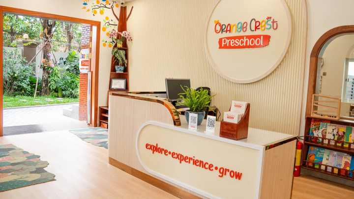 The reception desk at Orange Crest Preschool, with the round school sign behind it