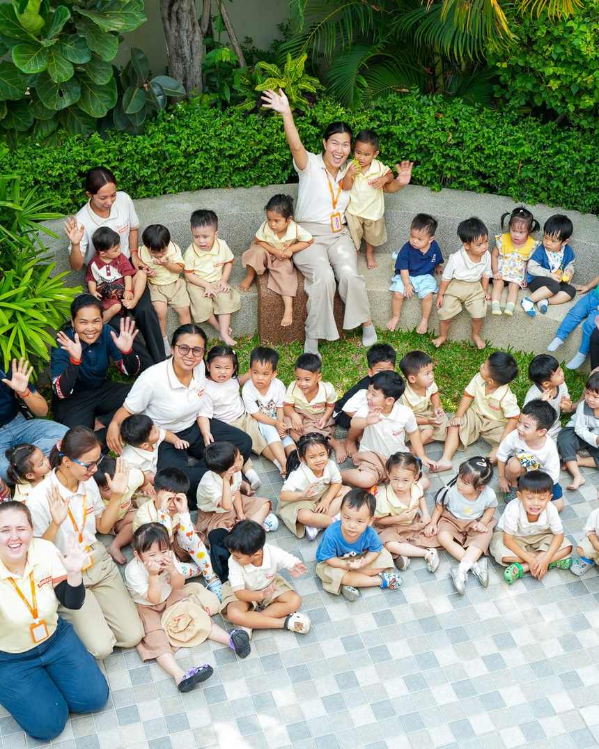 The children and staff of Orange Crest Preschool sitting together in the garden, waving
